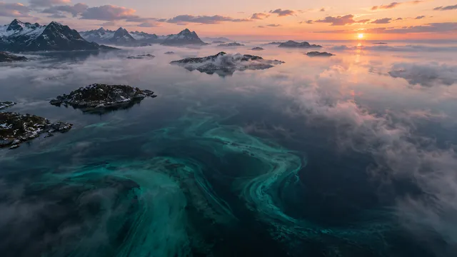 4K High-angle aerial drone shot at dawn over a glassy, calm misty Norwegian sea, 16:9 widescreen cinematic photograph shot on RED Digital Cinema Camera.