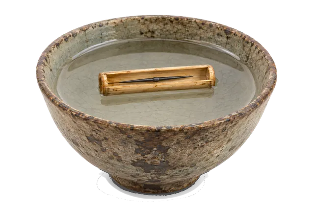 4K transparent cutout of product photography of a single ancient Chinese reed-float compass consisting of a rustic ceramic bowl filled with water where a magnetized iron needle rests inside a short piece…