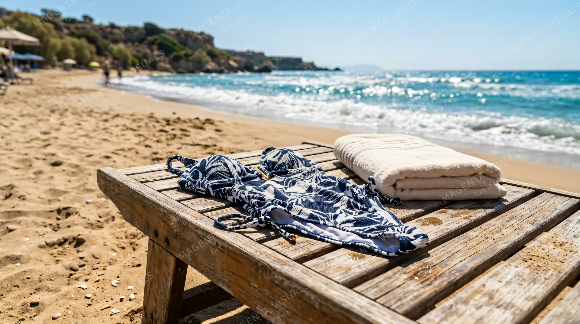 4K 16:9 photoreal photograph of a stylish swimsuit resting naturally on a wooden beach lounger next to a neatly folded cotton towel, set on a sun-drenched sandy coastline with the br…